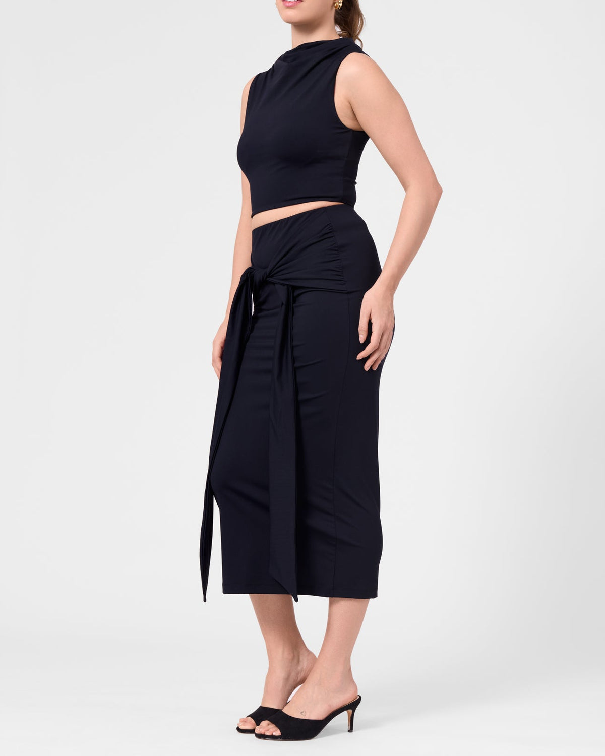 Model wearing the ROEM Itaso Front Wrap Skirt in Black, styled with the Grace Top, side view